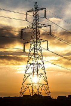 the sun is setting behind an electric tower