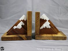 two wooden mountain bookends with white mountains on each one and brown wood in the middle