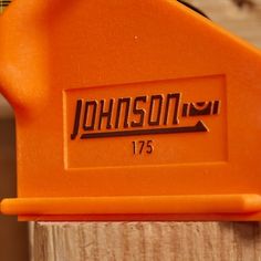 a close up of an orange tool on a piece of wood with the name johnson written on it