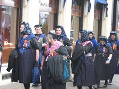 a group of people standing on the side of a road next to each other wearing costumes