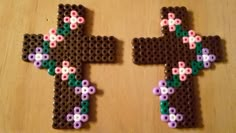 two cross made out of legos sitting on top of a wooden table next to each other