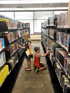 two children sitting on the floor in front of bookshelves and looking at each other