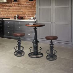 three stools sit in the middle of a kitchen with an island and brick wall