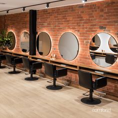 a row of chairs with mirrors on them in front of a brick wall and wooden floor