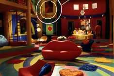 a brightly colored room with lots of furniture and decorations on the floor, including two red chairs