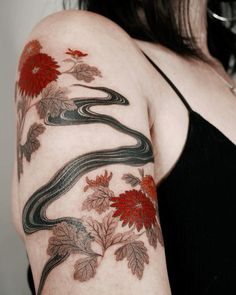 a woman's arm with a snake and flowers tattoo on her left side shoulder