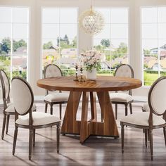 a dining room table with chairs around it and a vase on the table in front of large windows