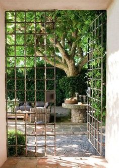 an open door leading to a patio area with chairs and trees in the back ground