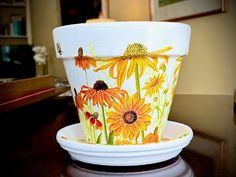 a flower pot sitting on top of a wooden table next to a white saucer