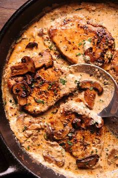 a skillet filled with chicken and mushrooms covered in gravy, garnished with parsley