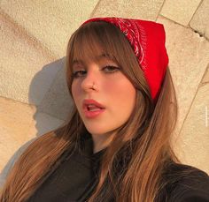 a woman with long hair wearing a red bandana on her head and looking off to the side