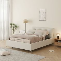 a white bed sitting next to a window in a bedroom on top of a hard wood floor