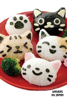 four sushi with cats and broccoli on a red plate, all decorated in black and white