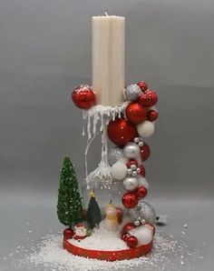 a candle is surrounded by christmas ornaments and baubles on a stand with snow