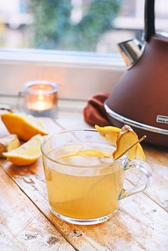 an apple cider with cinnamon and apples in the background on a wooden platter