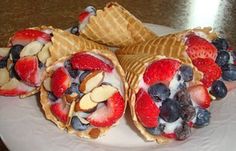 three waffles filled with fruit and nuts on a white plate next to a bowl of strawberries