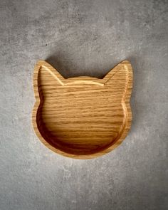 a wooden cat shaped dish on a gray surface