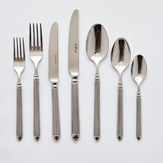 an assortment of silverware including forks, knives and spoons on a white surface