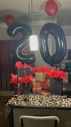 a table with presents and balloons in the shape of numbers on it, sitting next to a leopard print chair