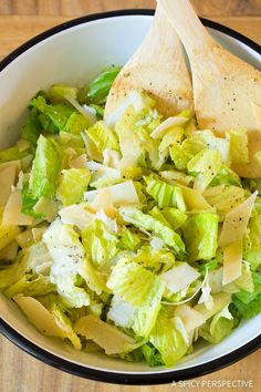 a salad with lettuce and parmesan cheese is in a white bowl