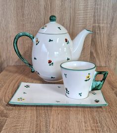 a tea pot and two cups sitting on a wooden table next to each other with matching placemats