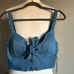 Trendy Denim Sleeveless Crop Top By Haute Monde Features A Built In Padded Chest And Thick Shoulder Straps. This Top Has Lots Of Stretch And There Is A Front Closure That Includes A Tie And 3 Snap Buttons. This Cute Crop Is Very Versatile! You Can Dress It Up Or Down, Layer It, And It Also Pairs Well With Other Denim * Please Note There Is A Flaw Shown In The Last Photo - The Back Piece Of The Middle Snap Button Is Missing. Super Easy Fix And The Button Replacement Can Be Found At Walmart For $1 Trendy Medium Wash Vest Top, Medium Wash Denim Vest Top For Summer, Summer Medium Wash Denim Vest Top, Sleeveless Denim Vest For Summer Day Out, Blue Denim Vest For Summer Days, Summer Blue Denim Vest For Day Out, Blue Denim Vest For Summer Day Out, Medium Wash Sleeveless Vest Top, Denim Sleeveless Tank Top For Summer