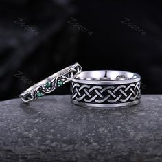 two wedding rings sitting on top of a rock with one ring in the middle and another in the back