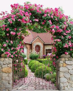 a house with pink flowers on the top of it's roof and an iron gate