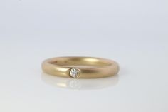 a yellow gold ring with a single diamond in the center on a plain white surface