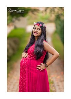 a pregnant woman in a pink dress poses for a photo with her hands on her hips