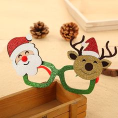 two paper reindeers with santa hats and glasses on their heads, standing next to pine cones