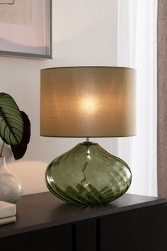 a green lamp sitting on top of a wooden table