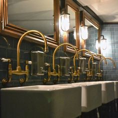 a row of sinks in a public restroom with mirrors and lights on the wall above them