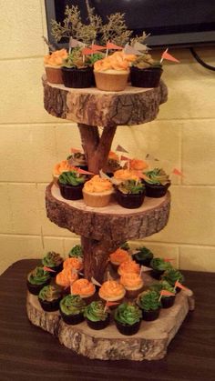 a three tiered cake stand with cupcakes on it and flowers in the center