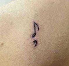 a small musical note tattoo on the back of a woman's shoulder