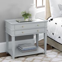 a bedroom with a white bed and gray nightstand table next to a small plant on top of the night stand