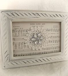 an old sheet music with a flower in the middle is framed on a white wall