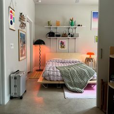 a small bedroom with a bed, lamp and pictures on the wall above it's headboard