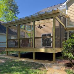 a screened in porch with a clock on the front and side of it that is attached to a house