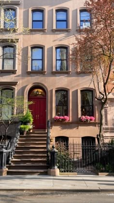 an apartment building with stairs leading up to the front door and flowers on the steps