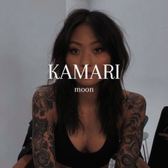 a woman with tattoos sitting in front of a wall and the words kaamari on it