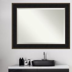 a bathroom with a sink and mirror on the wall next to a counter top that has a black bowl under it