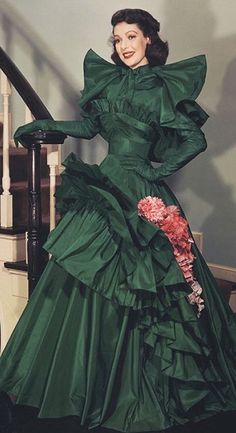 a woman in a green dress standing on some stairs