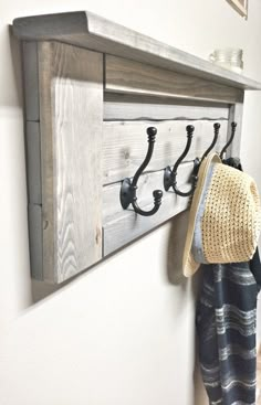 a hat and coat hanger on a wooden shelf next to a towel rack with hooks