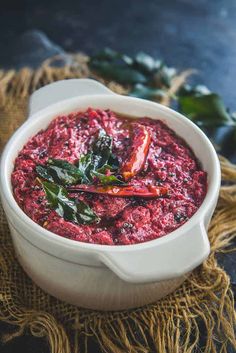 a white bowl filled with red sauce and greens