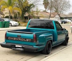 a blue pick up truck parked on the side of a street