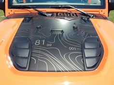 the hood of an orange sports car with numbers on it