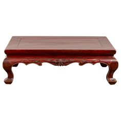 a wooden coffee table with carvings on the top and bottom, sitting against a white background