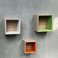 three wooden boxes with different colors and shapes on the wall next to each other,