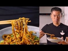 a man holding a bowl full of food and chopsticks in front of him